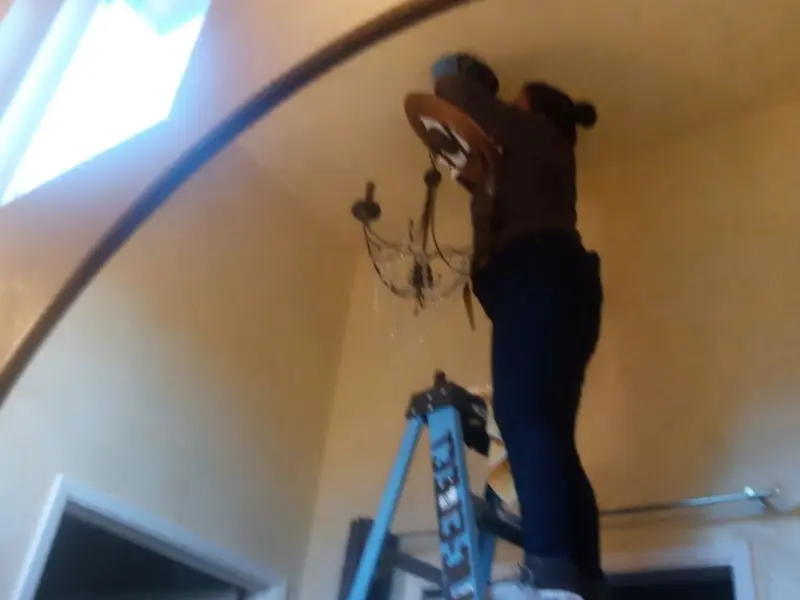 Electrician installing a chandelier in a Muscoy residence